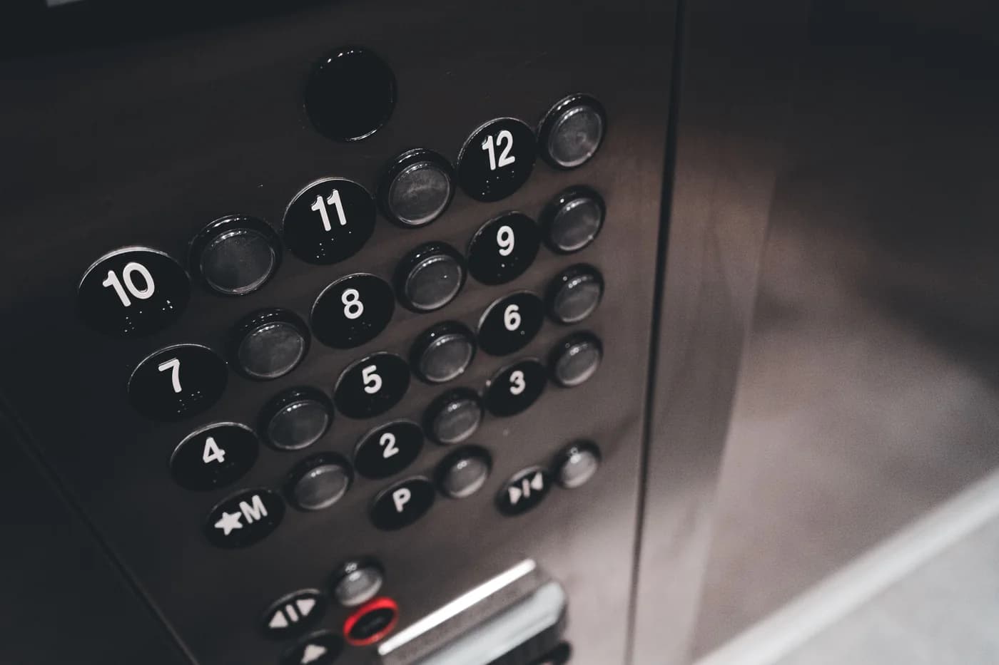 Botonera de ascensor de un edificio residencial, pisos 1 al 12; fotografía de Introspective Design en Pexels.