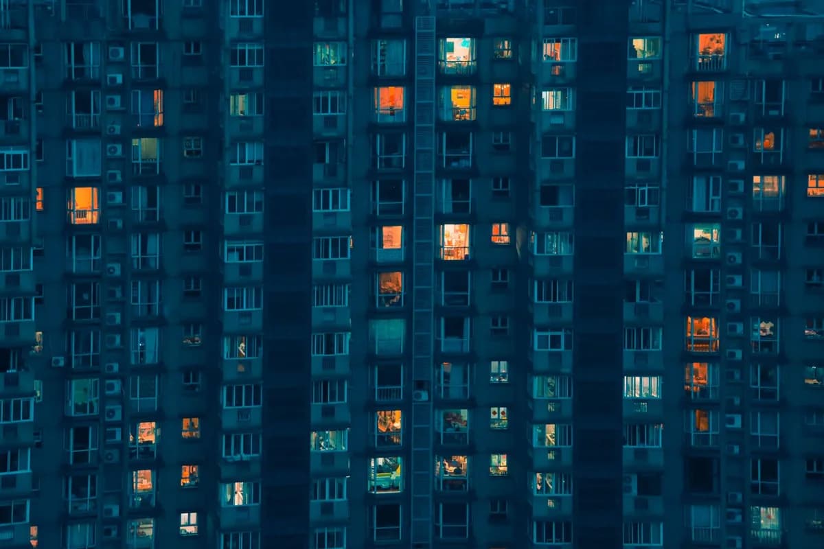 Fachada de un edificio de departamentos de noche, con algunas ventanas todavía iluminadas; fotografía en Pexels.