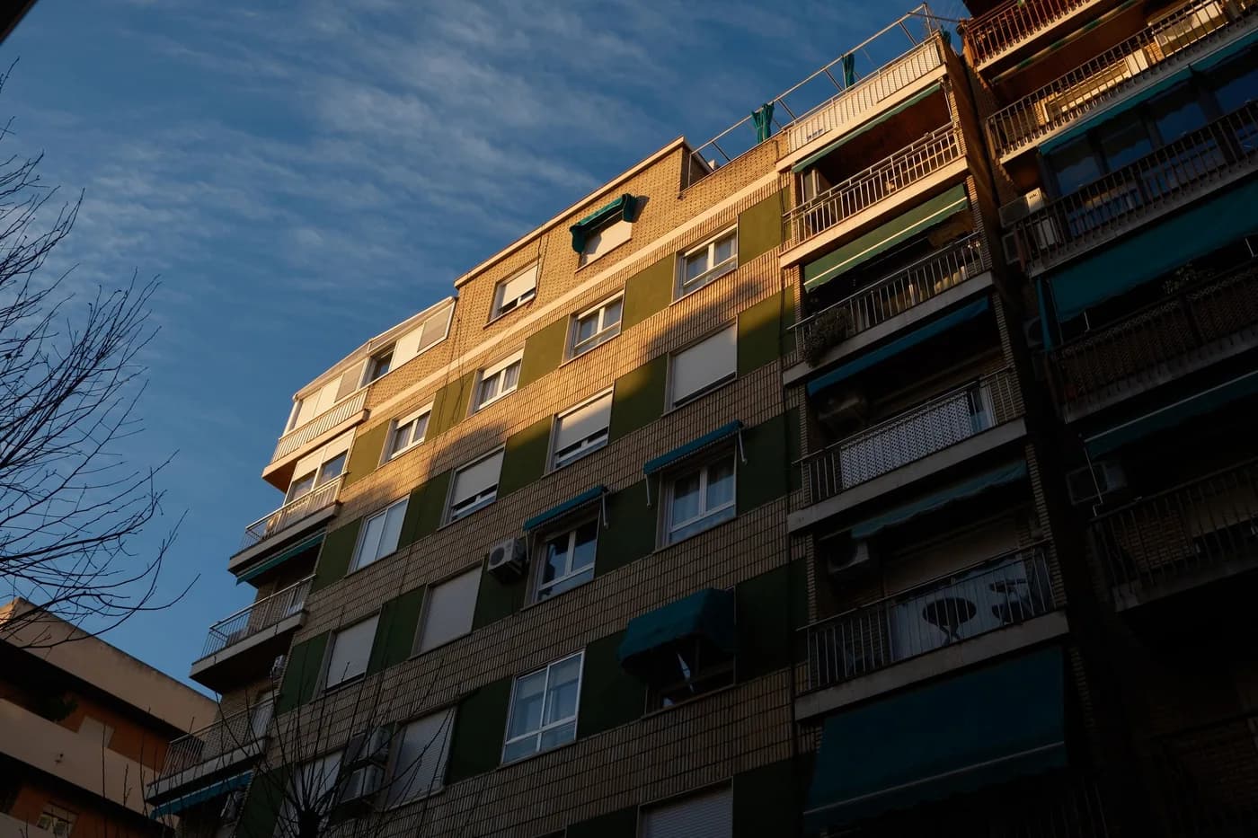 Fachada de un edificio residencial de departamentos con balcones, a la luz del atardecer; fotografía de Ramon Karolan en Pexels.